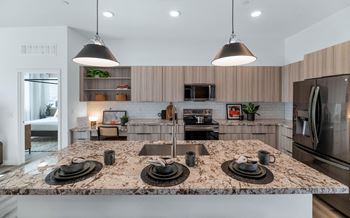 A kitchen with a granite countertop and stainless steel appliances.